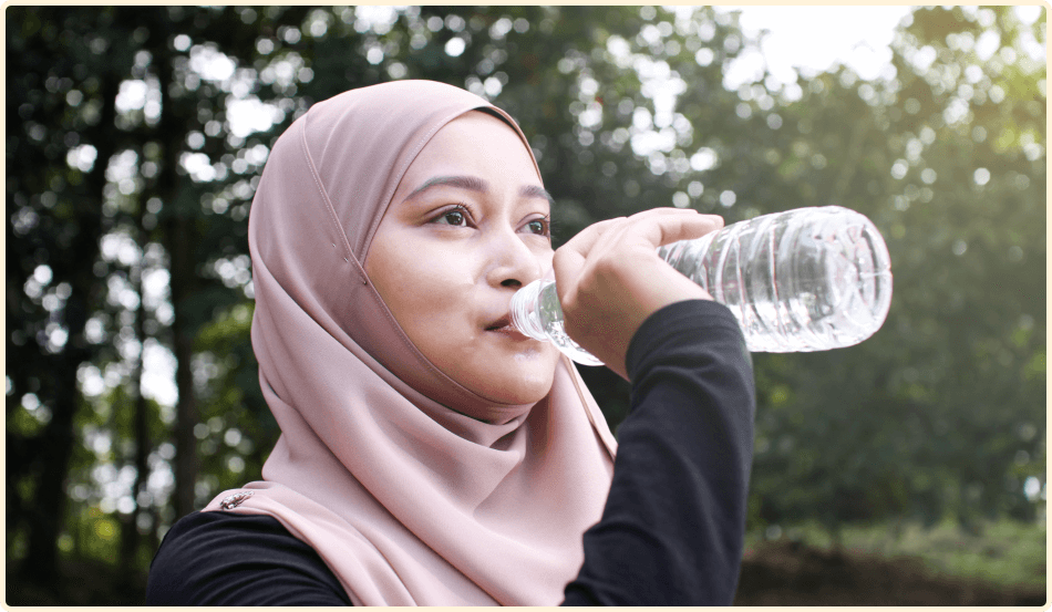Une jeune femme qui boit de l’eau à la bouteille. 