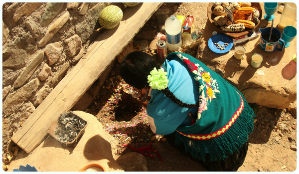 Une femme d’Amérique du Sud en costume traditionnel dépose une offrande dans un trou. 