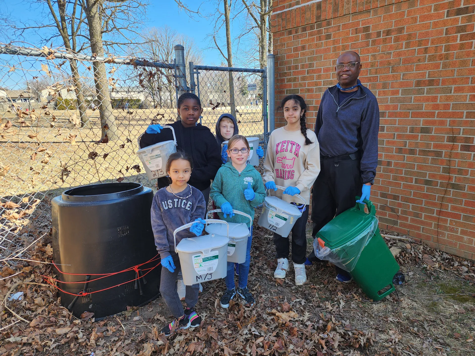 Photo d'un adults et de cinq enfants en train de composter.