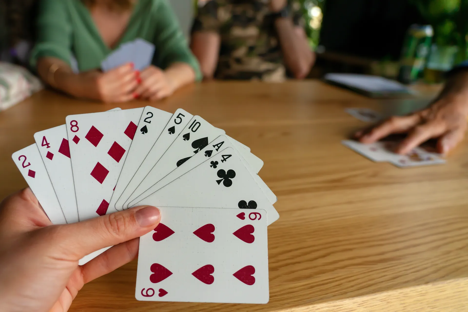 Trois personnes jouent aux cartes. 