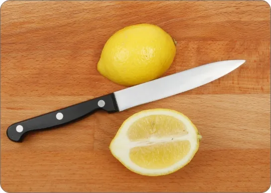 Photo d'un citron coupé en deux et un couteau sur une planche à découper.