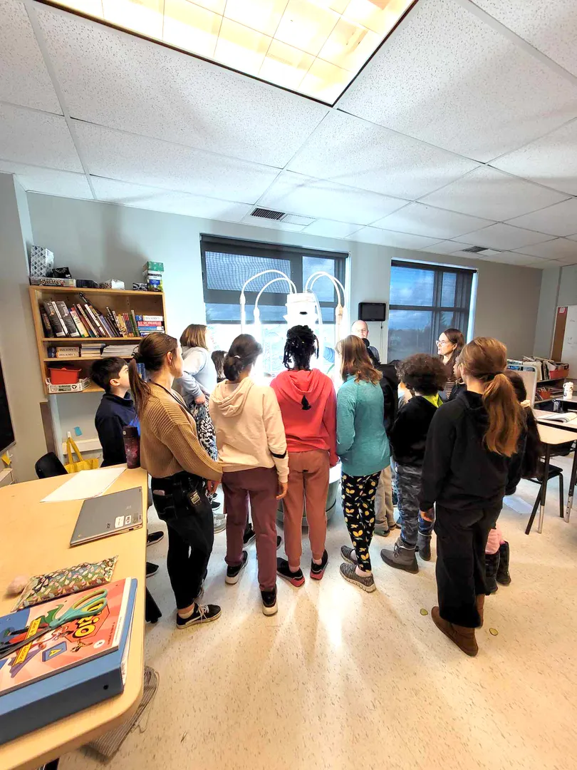 Photo d’élèves debout dans une classe.  