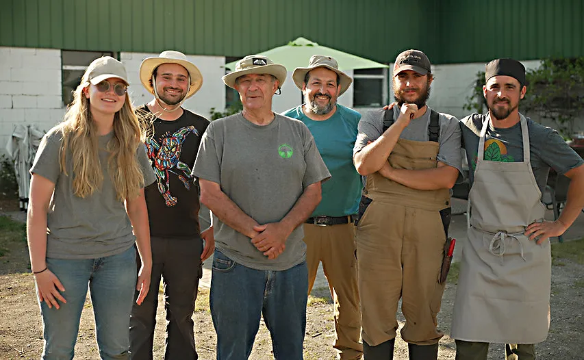 Photo de Robert Poirier et six membres de son équipe, à l’extérieur, en été.
